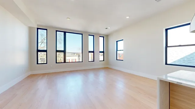 a view of an empty room with a window and wooden floor