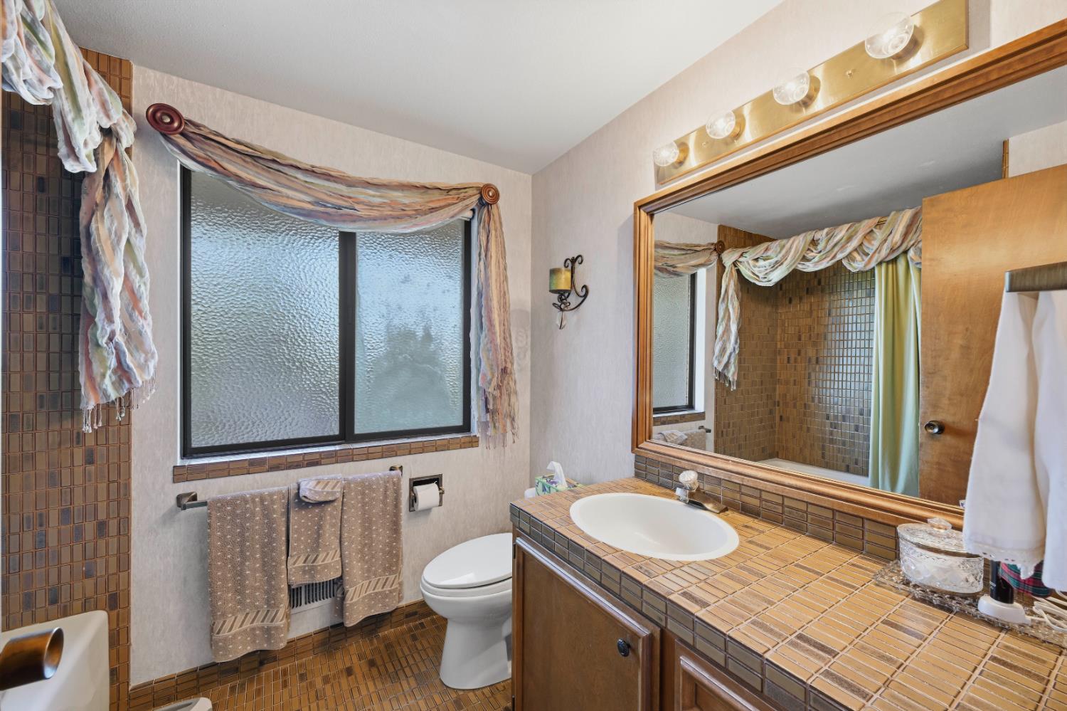 8860 Auburn Valley Road Auburn, CA 95602 - Photo 30 of 46 a bathroom with a granite countertop sink toilet a mirror and shower