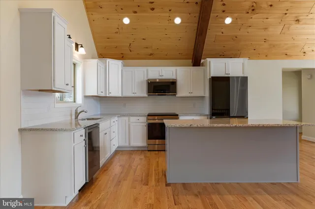 a kitchen with stainless steel appliances a stove top oven a sink a microwave a refrigerator and cabinets