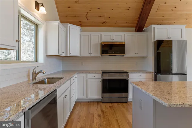 a kitchen with granite countertop a sink stove and refrigerator