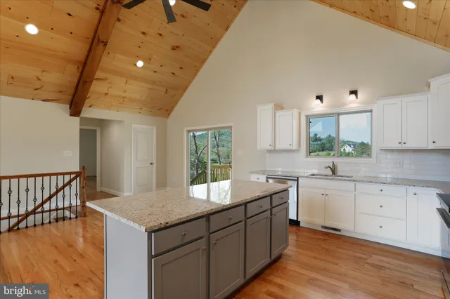 a kitchen with granite countertop a sink and dishwasher a stove top oven with wooden floor