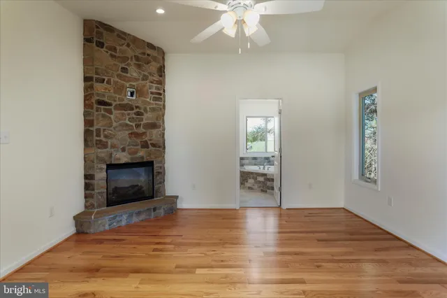 an empty room with wooden floor fireplace and windows