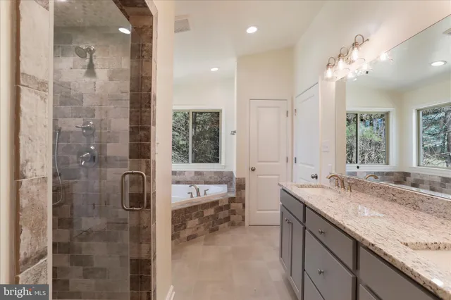 a spacious bathroom with a granite countertop sink a large mirror and a shower