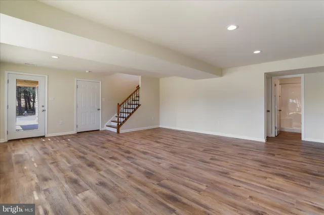 a view of an empty room with wooden floor and stairs
