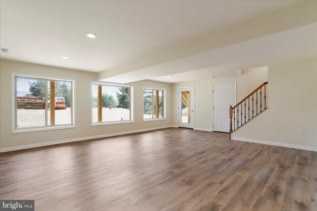 a view of an empty room with wooden floor and windows