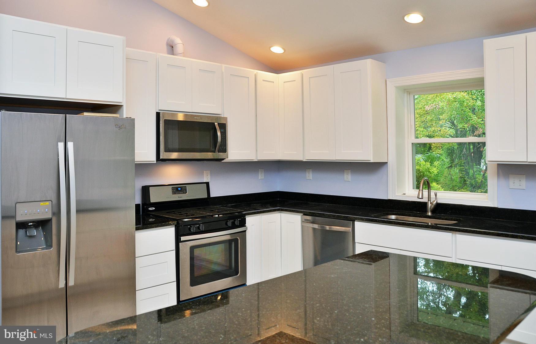 9710 Holmhurst Road Bethesda, MD 20817 - Photo 2 of 18 a kitchen with granite countertop a refrigerator sink and microwave