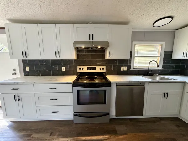 a kitchen with granite countertop a sink and a stove