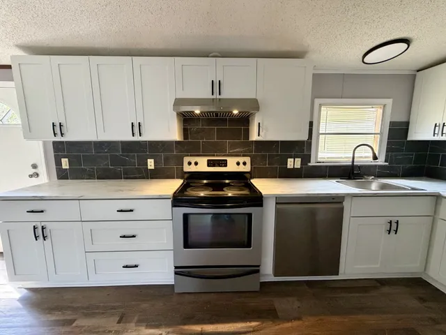 a kitchen with granite countertop a sink and a stove