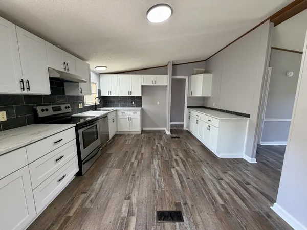 a kitchen with granite countertop a stove top oven a sink dishwasher and a refrigerator with wooden floor