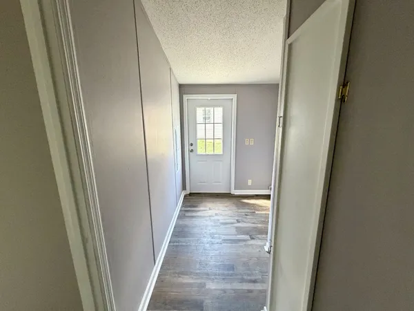 a view of a hallway with wooden floor and closet