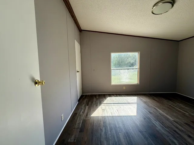 an entryway of an empty room with wooden floor and a window