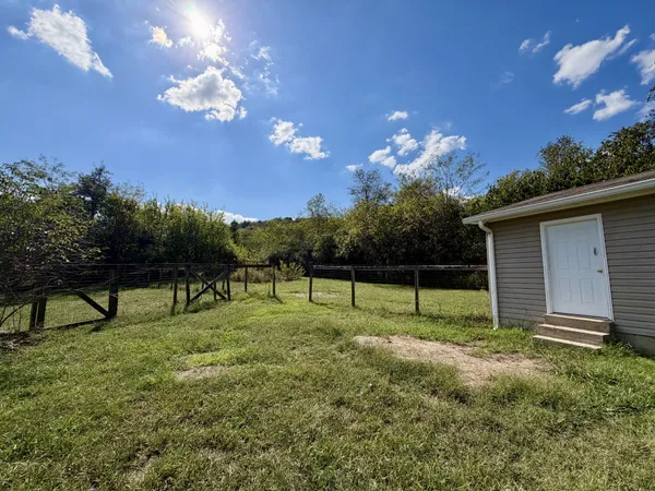 front view of house with yard and trees in the background