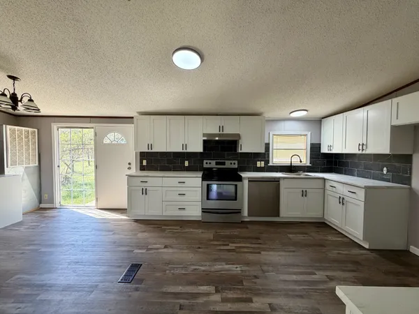 a kitchen with granite countertop a stove top oven sink and cabinets