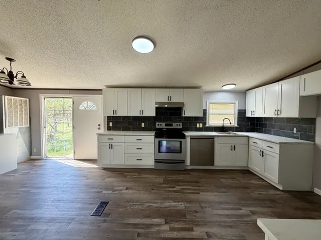 a kitchen with granite countertop a stove top oven sink and cabinets