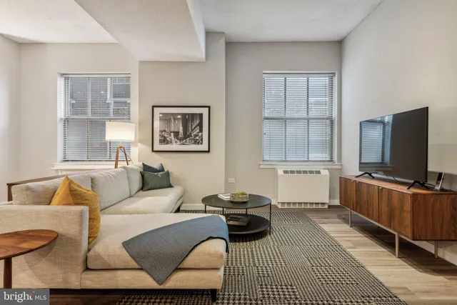 a living room with furniture a flat screen tv and a window