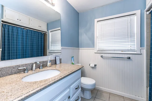 a bathroom with a granite countertop sink toilet and mirror