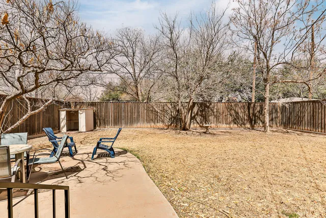 a view of a backyard with table and chairs under a large tree