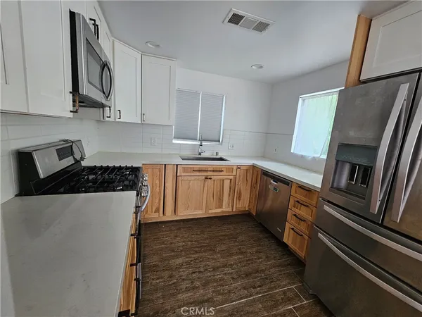 a kitchen with stainless steel appliances a refrigerator a sink a stove and white cabinets
