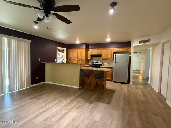 a kitchen with stainless steel appliances a stove a refrigerator a sink a stove white cabinets and wooden floor