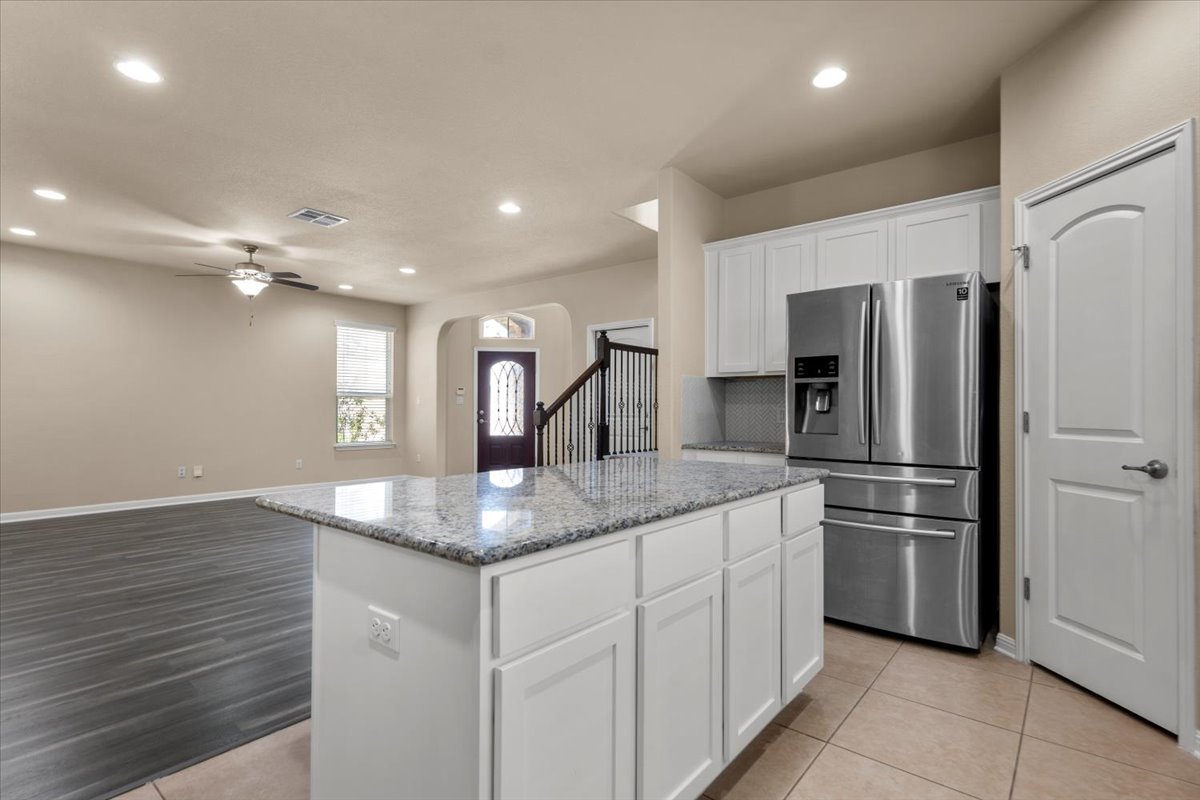 3451 Mayfield Ranch Boulevard, Unit 311 Round Rock, TX 78681 - Photo 12 of 40 Kitchen island with granite countertop and white cabinetry