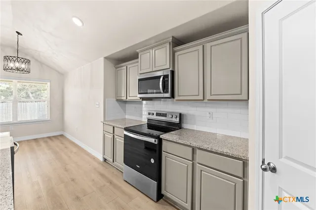 a kitchen with stainless steel appliances granite countertop a stove a sink and a microwave