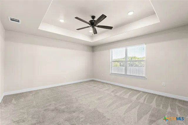 an empty room with ceiling fan and windows