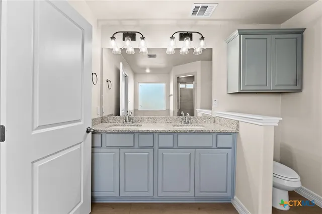 a bathroom with a granite countertop toilet sink and mirror