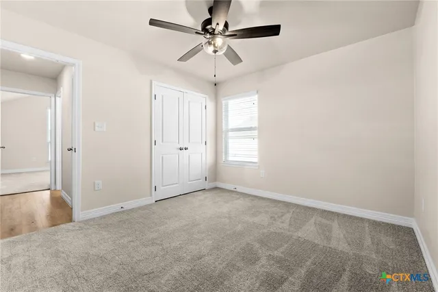 an empty room with windows and fan