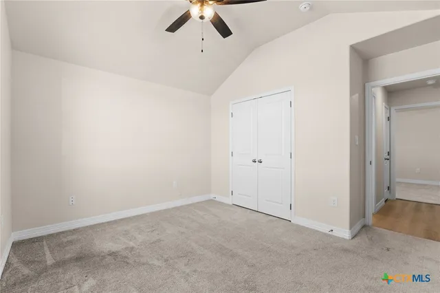 an empty room with a ceiling fan and carpet