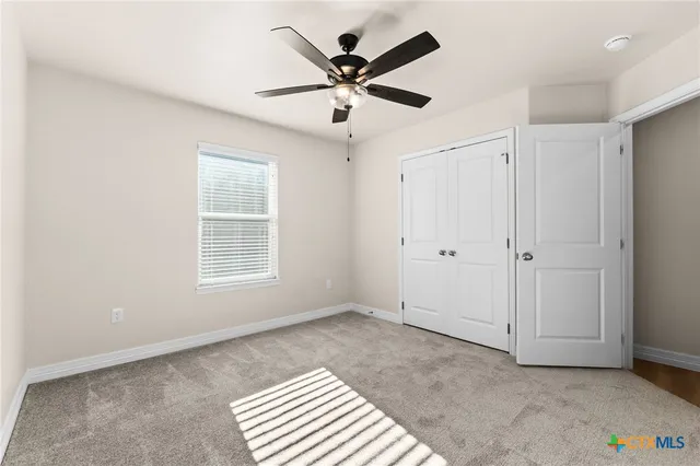 a view of an empty room with a ceiling fan and a window
