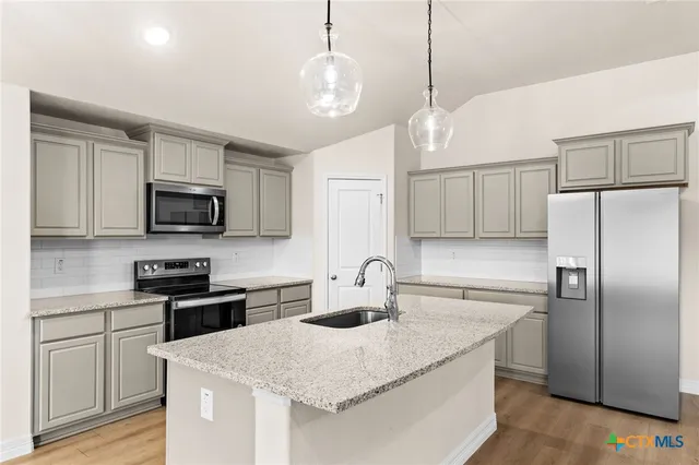 a kitchen with stainless steel appliances granite countertop a sink a stove a refrigerator cabinets and chairs