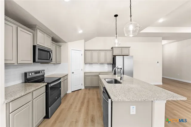a kitchen with granite countertop a sink a counter top space stainless steel appliances and cabinets