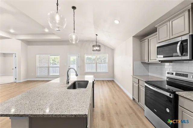 a kitchen with stainless steel appliances granite countertop a sink dishwasher a microwave oven a stove with granite countertops and cabinets