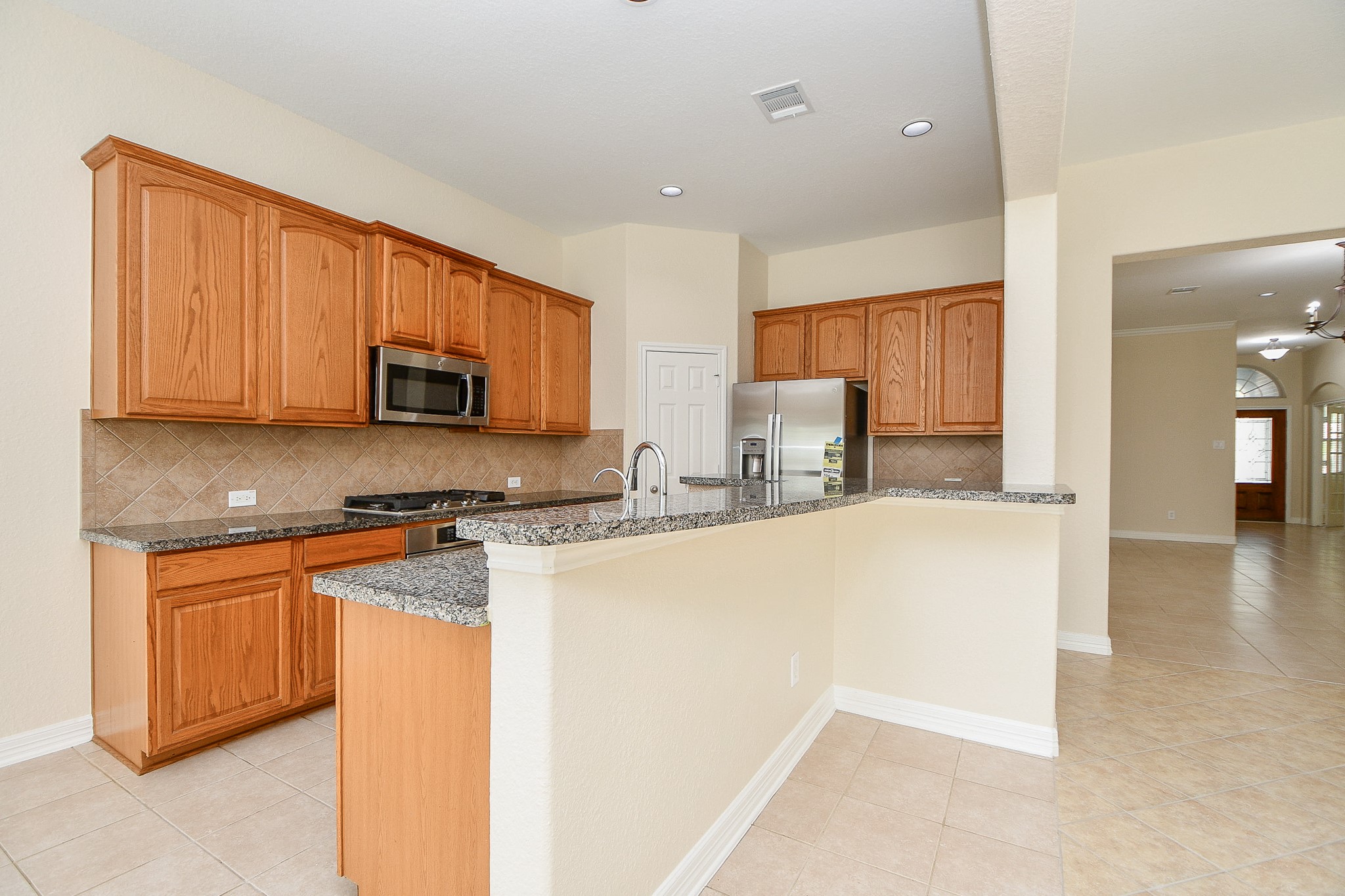 12104 Dawn Mist Court Pearland, TX 77584 - Photo 23 of 31 a kitchen with stainless steel appliances granite countertop a stove top oven a sink a refrigerator white cabinets and wooden floor