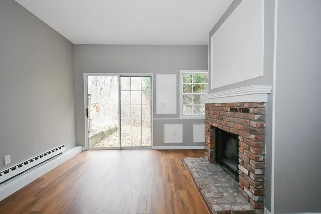 an empty room with wooden floor fireplace and windows