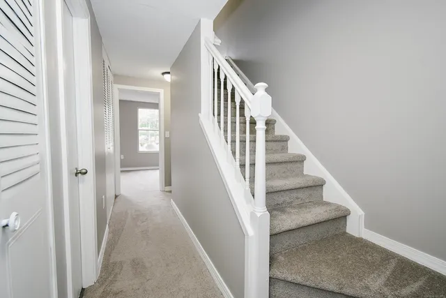 a view of staircase with lots of frames on wall and wooden floor