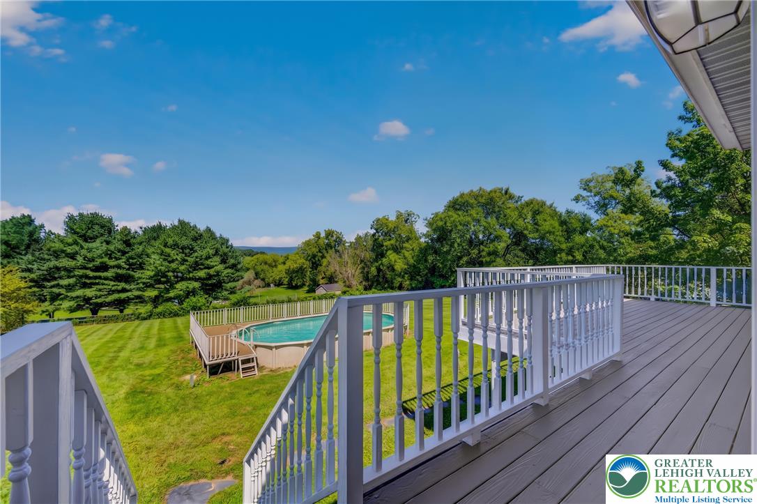 630 Clearfield Road Nazareth, PA 18064 - Photo 91 of 100 An elevated wood deck overlooks a lush green yard with an above-ground pool.