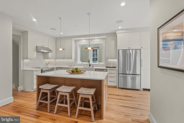 a kitchen with kitchen island wooden cabinets and refrigerator
