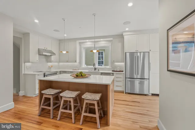 a kitchen with kitchen island wooden cabinets and refrigerator