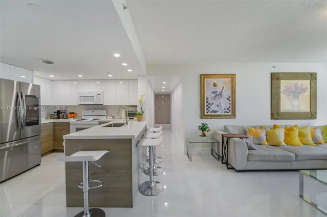 a living room with stainless steel appliances furniture and a kitchen view