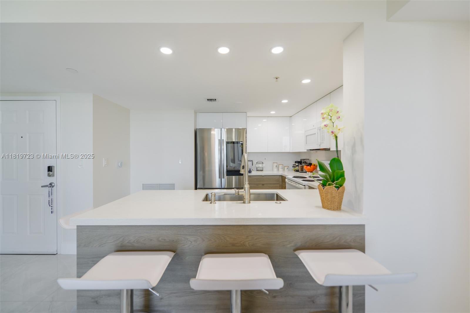 3000 Coral Way, Unit 1208 Miami, FL 33145 - Photo 8 of 35 a kitchen with stainless steel appliances a table and chairs in it