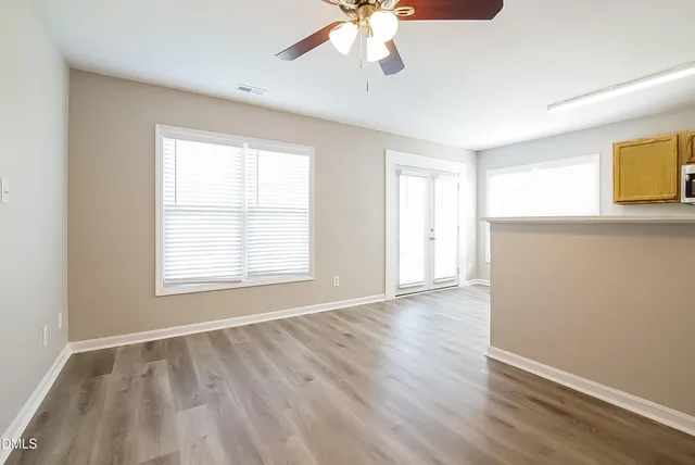 a view of an empty room with window and wooden floor