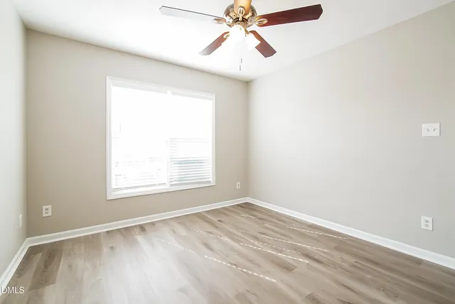 an empty room with a window and a fan