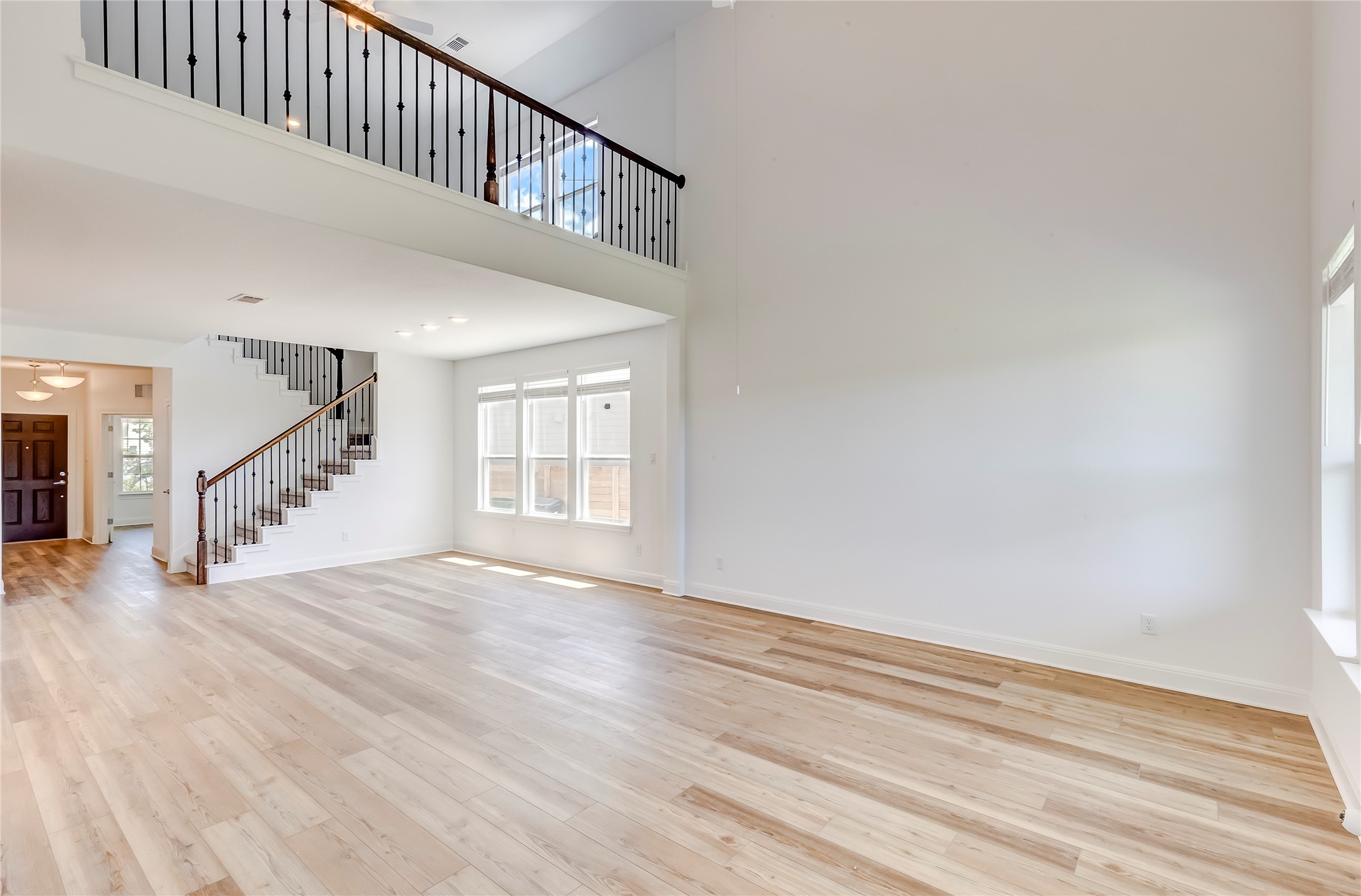 132 Inlet Lane Leander, TX 78641 - Photo 10 of 36 Unfurnished living room featuring stairway, plenty of natural light, light wood-type flooring, and a towering ceiling