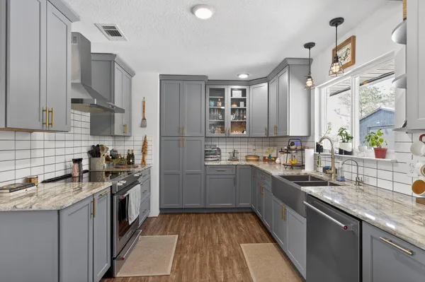 a kitchen with stainless steel appliances granite countertop a dining table chairs refrigerator and chandelier