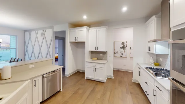 a kitchen with stainless steel appliances a stove top oven a sink a refrigerator white cabinets and wooden floor