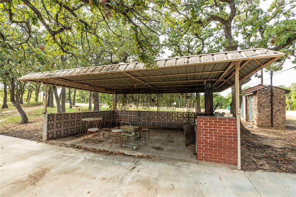 722 Storey Road Nocona, TX 76255 - Photo 32 of 40 a view of a patio with a table and chairs under an umbrella with a small yard