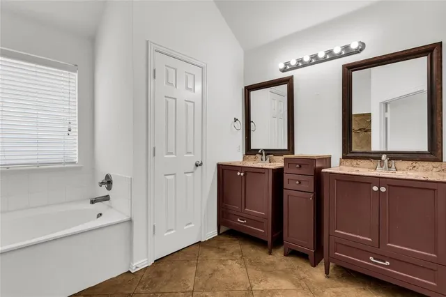a bathroom with a tub a double vanity sink and mirror