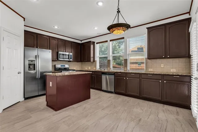 a kitchen with stainless steel appliances granite countertop a stove a sink and a refrigerator