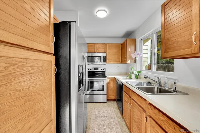 a kitchen with granite countertop stainless steel appliances a sink window and cabinets